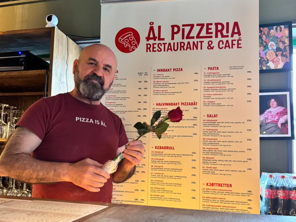 Bilde av eieren på Ål Pizzeria med en blomst i hånden