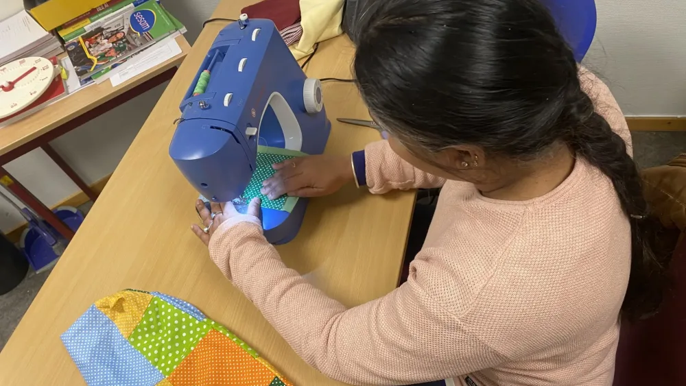 bilde av ei dame som fikser klærne sine på symaskin